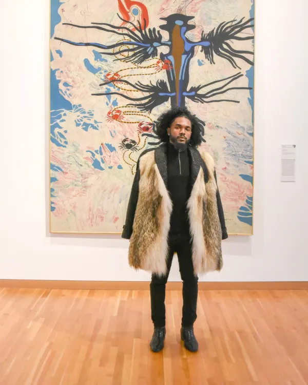 Mack standing in front of one of his paintings at a gallery